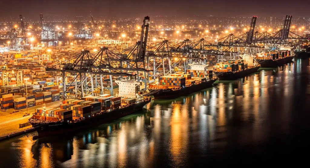 Port kontenerowy nocą z oświetlonymi statkami